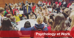 Students gather around a circular table, listening to an alum speak at the 2021 Psychology at Work.